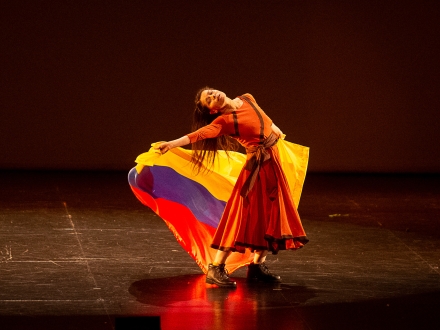 Bailarina con bandera de Colombia en un escenario. 