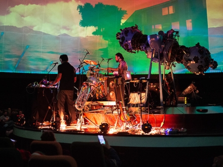 Agrupación musical tocando en vivo en tarima del domo del Planetario de Bogotá con proyección audiovisual. 
