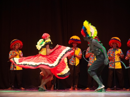 Dos bailarines en tarima con músicos de fondo 