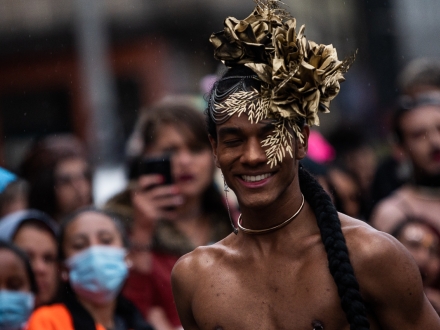 Artista trans con un tocado dorado hace voguing en las afueras del Castillo de las Artes, de día.