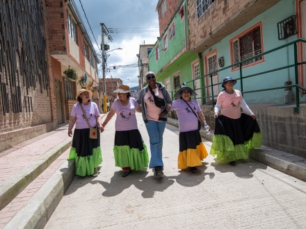 Cinco mujeres caminando por una calle de Ciudad Bolívar de día.