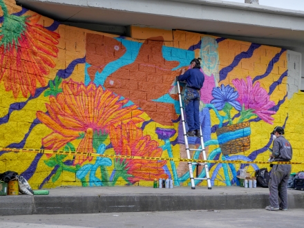 El costado de una zona bajo puente siendo intervenido por un par de artistas