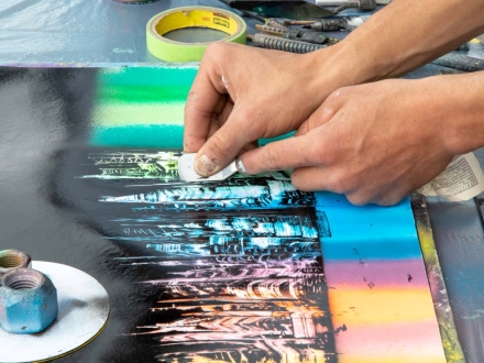 Manos de artista con espátula sobre obra de arte de día. 