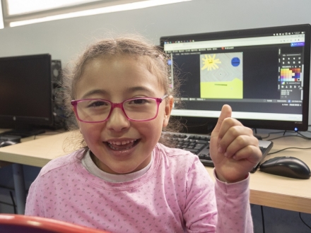 Una niña sonríe frente a un computador
