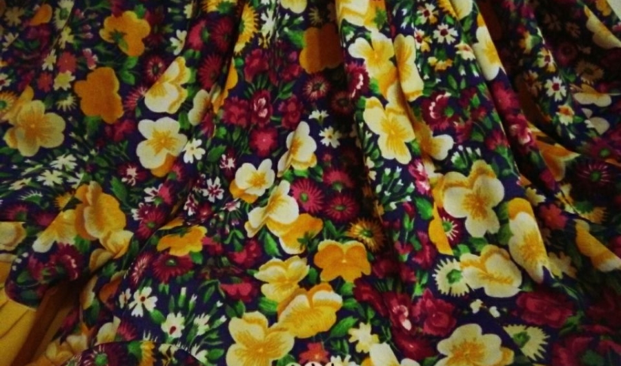 Falda de flores con las letras de la obra en un collar de cuadritos