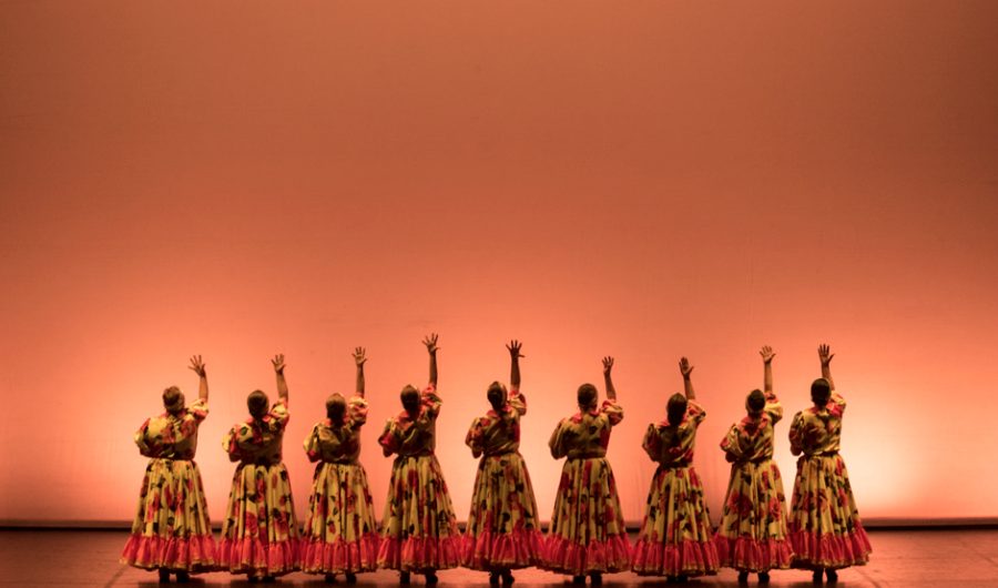 Mujeres danzando en el escenario con trajes coloridos.