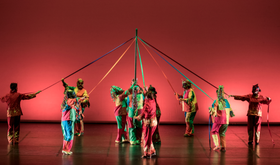 Grupo de bailarines con lazos de colores entrelazados en el escenario