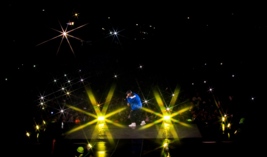 Hombre en una tarima cantando en un concierto realizado en la noche.