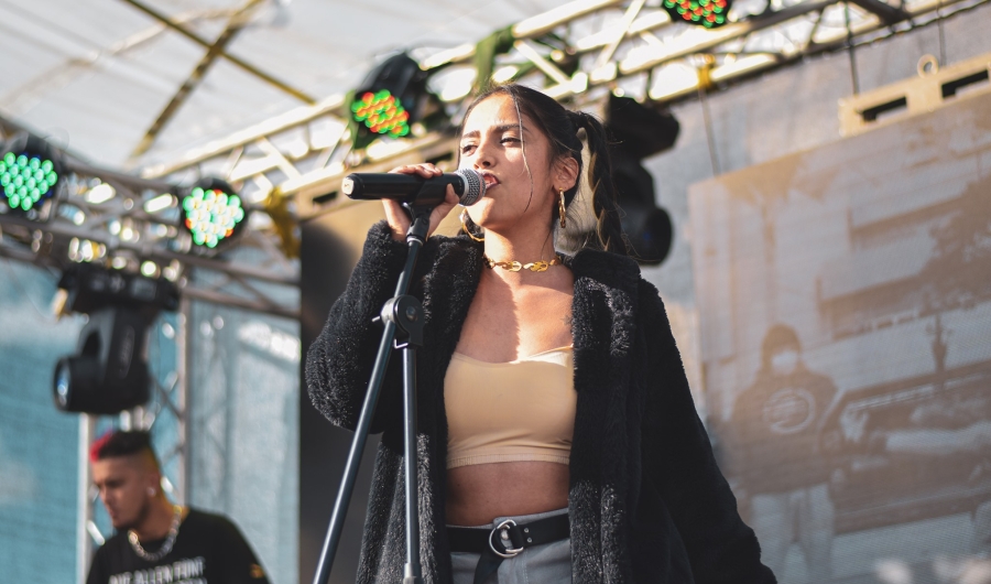 Fotografía de una mujer en escena cantando frente a un micrófono