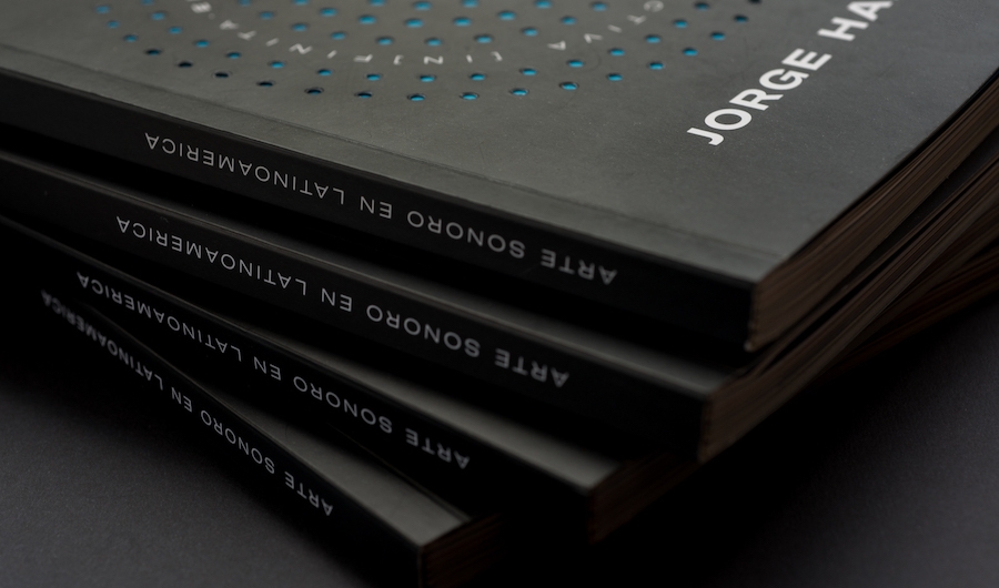 Cuatro libros negros apilados en un fondo negro. 