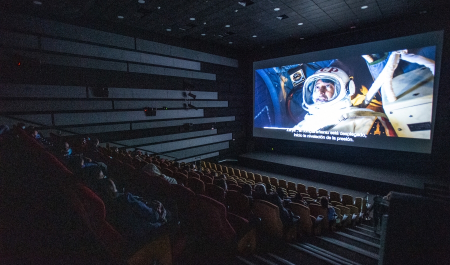 Sala oscura de Cinemateca con proyección de astronauta de fondo. 