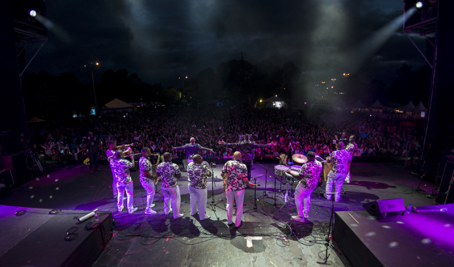 Personas en escena con instrumentos y público en la noche