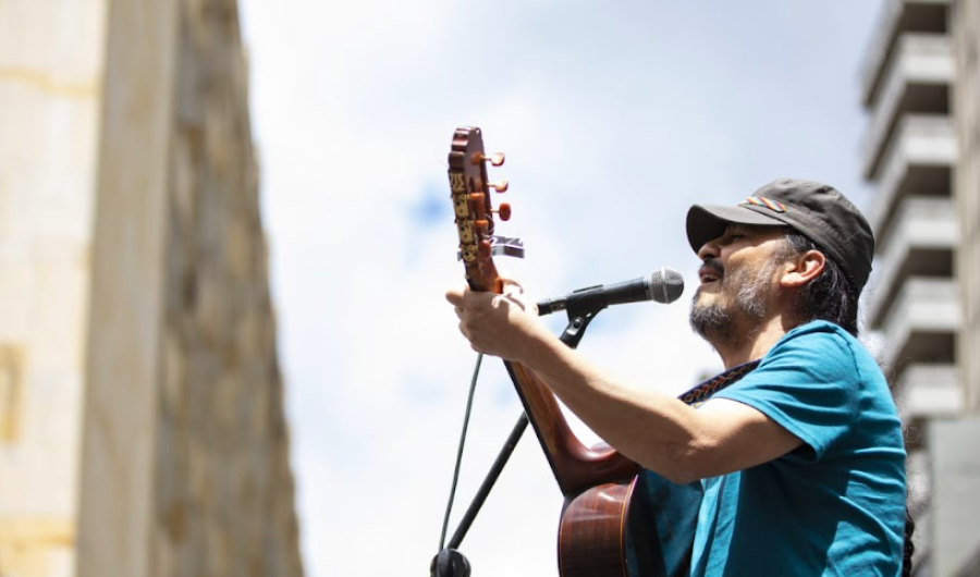 Señor con camiseta azul cantando en una tarima