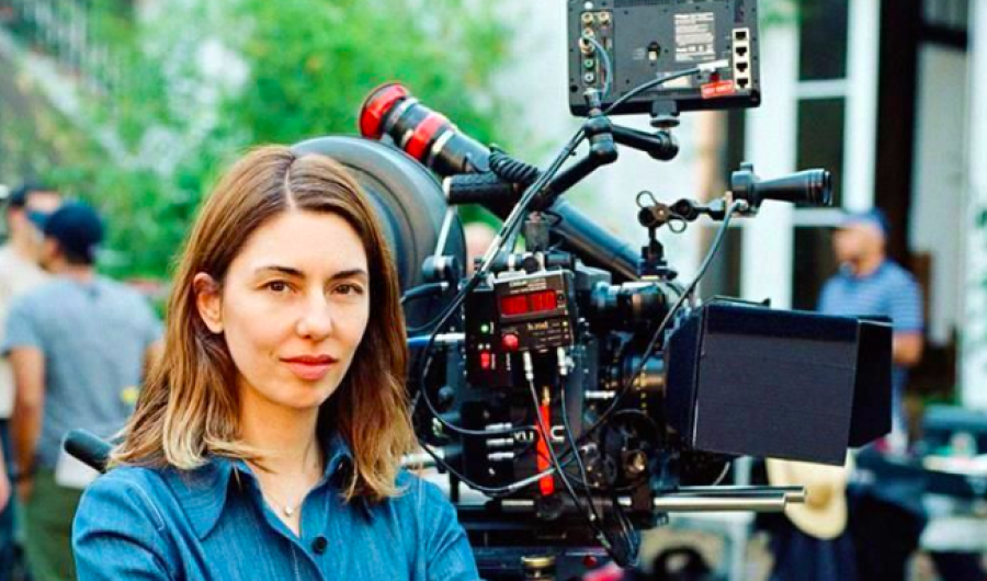 Mujer posando con cámara de cine de fondo