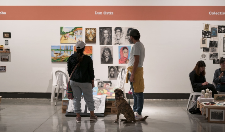 Dos personas y un perro admiran las obras en un stand de las Ferias Locales de Artes en La Candelaria
