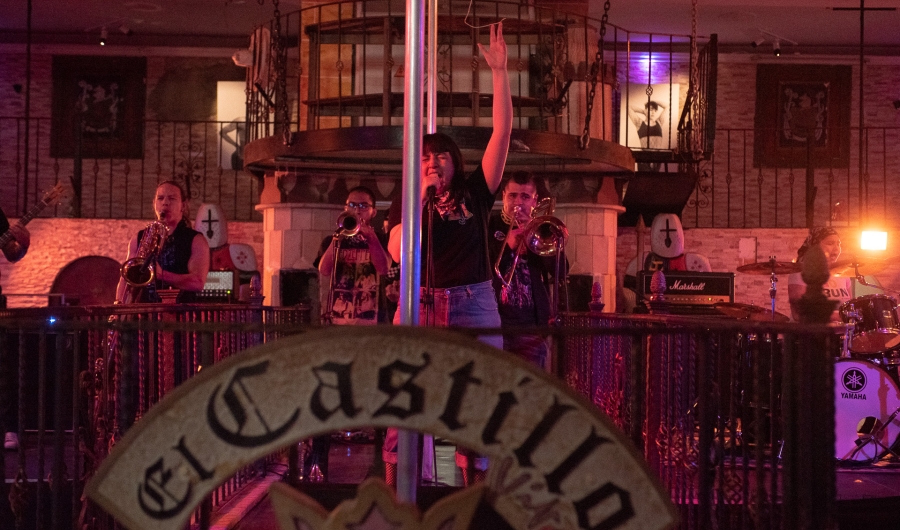 Música cantando con trompetistas de fondo con ambiente tenue