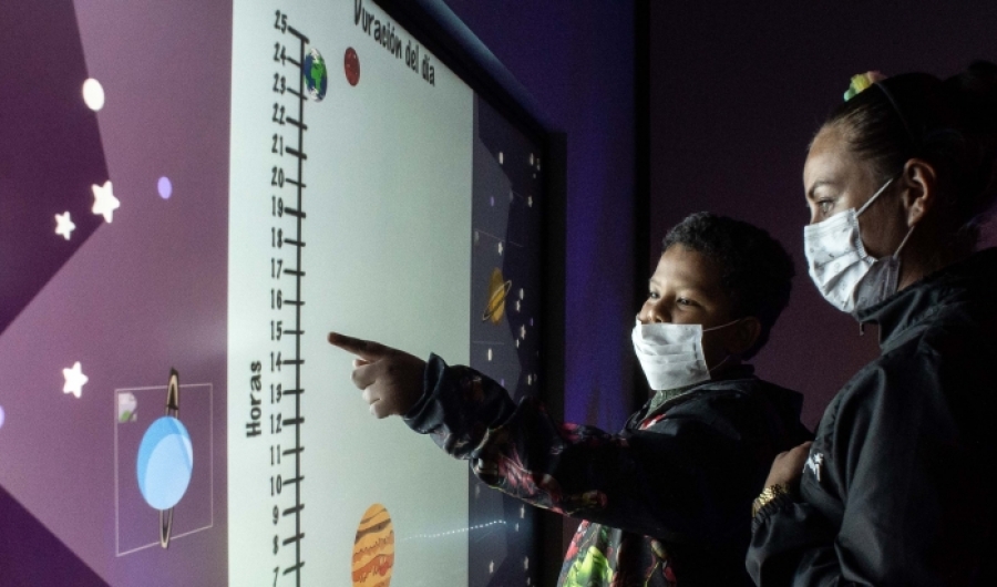 Dos personas con una pantalla táctil en el Planetario.