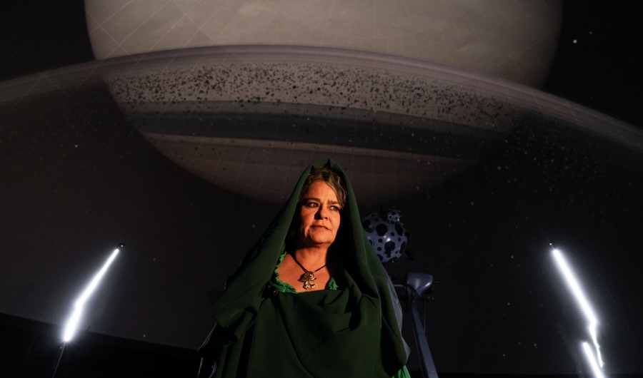 Carolina Rueda enfrente de una proyección de Saturno en el domo.