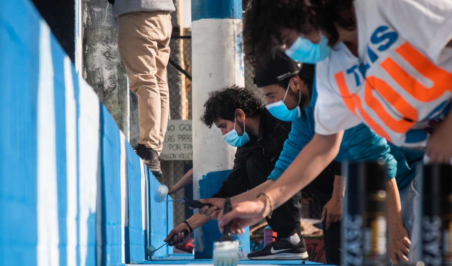 Grupo de personas pintan una zona bajo puente con rodillos