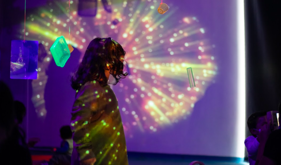 Niño con un juguete en la mano en un cuarto con luces neón