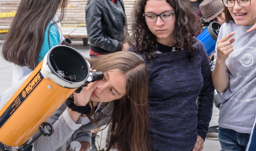 Niñas observando por telescopio. 