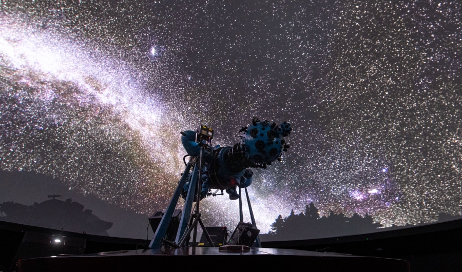 Proyector óptico mecánico en el domo con proyección del cielo de fondo.