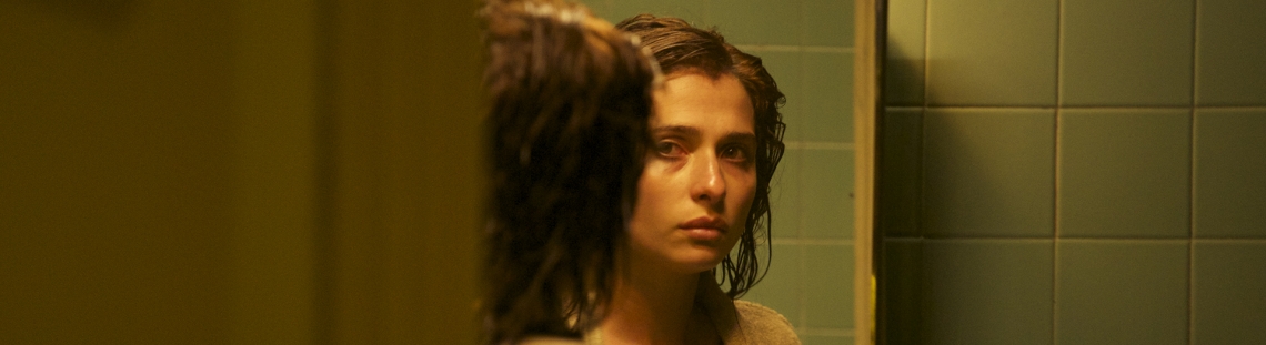 Mujer frente al espejo en un baño de luz tenue.