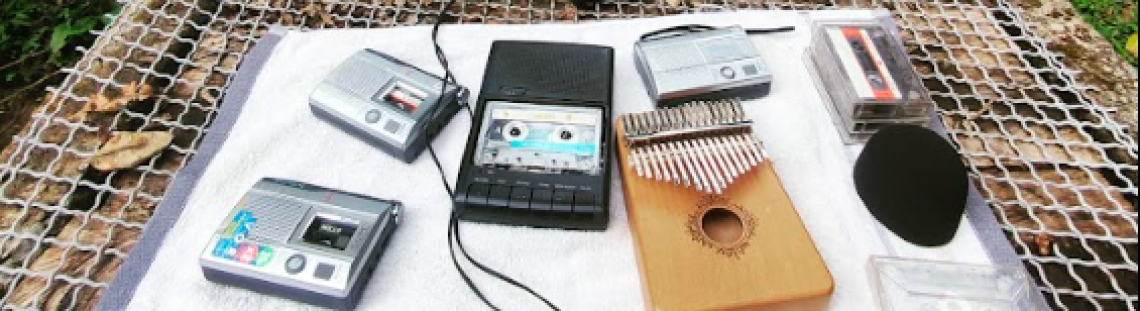 Superficie con objetos como grabadora, walkman, casette, instrumento musical