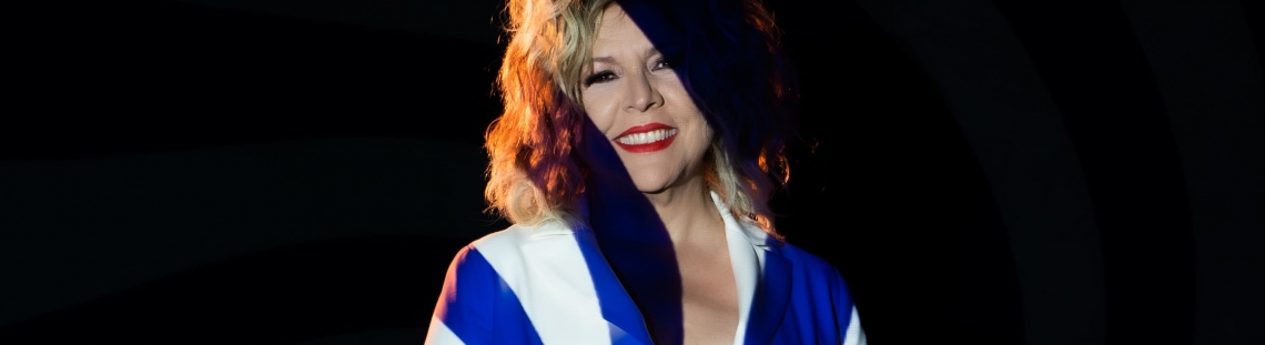 Albita Rodríguez fondo negro y vestida de enterizo azul con blanco 