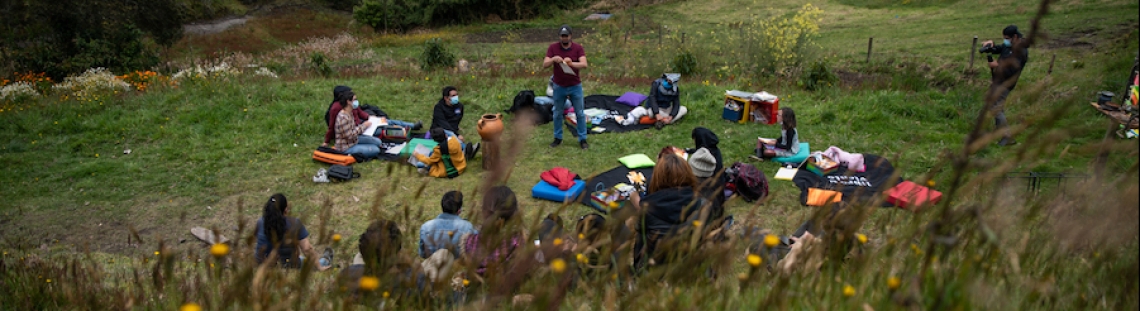 Jóvenes y niños en un campo hablando con mediadior del Planetario. 