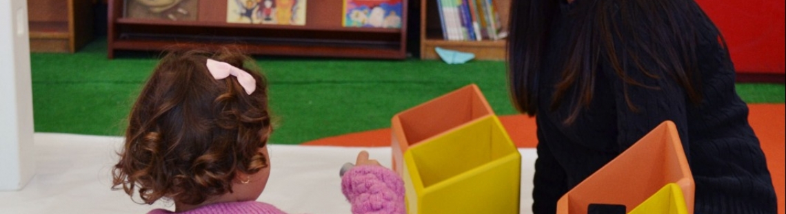 Bebé con cuidadora en sala de lectura infantil