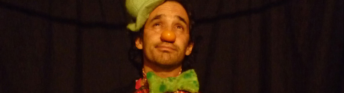 Actor títere en el escenario con sombrero verde y chaleco de cuadros rojos