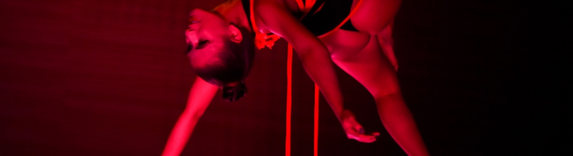 Mujer suspendida en cuerdas con luz roja. 