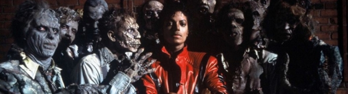 Michael Jackson en traje rojo entre varios zombies en famoso video de Thriller. 