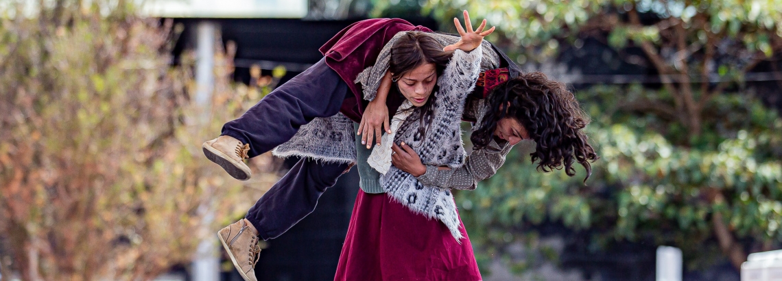 Mujer carga a hombre en una obra de teatro. 