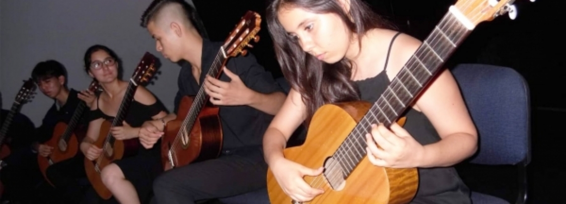 Joven interpretando la guitarra vestida de negro