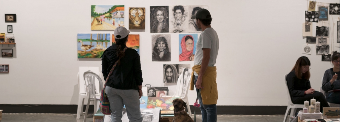 Pareja y perro observando los puestos de los artistas de las FLA en La Galería Santa Fe