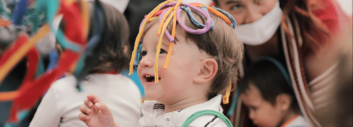 Bebé disfrutando de un laboratorio artístico de día y con más niños al fondo.