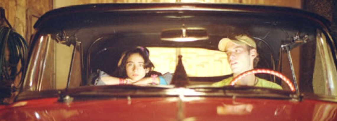 Niño y joven montados en un carro rojo 