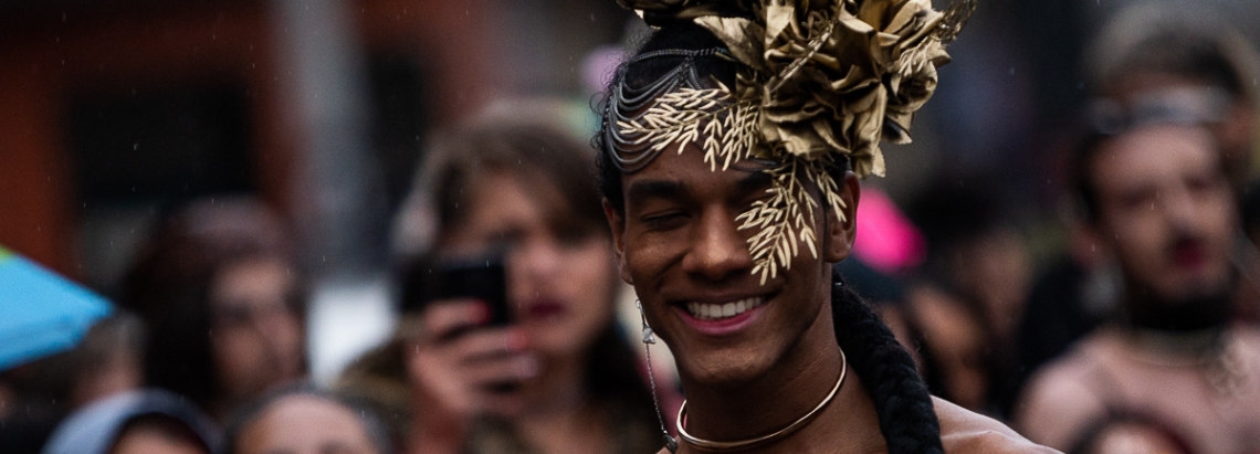 Artista trans con un tocado dorado hace voguing en las afueras del Castillo de las Artes, de día.