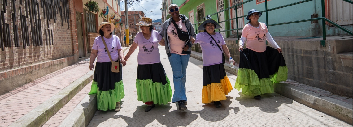 Cinco mujeres caminando por una calle de Ciudad Bolívar de día.