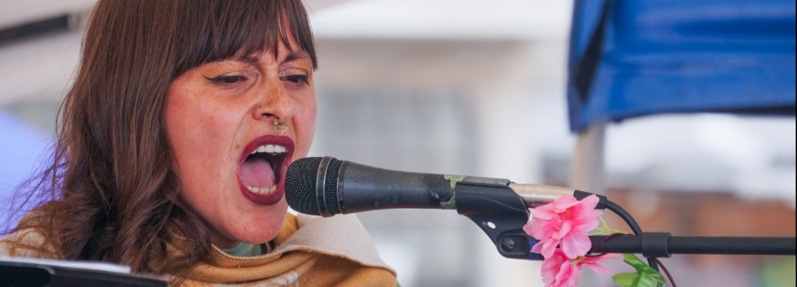 Mujer canta frente a un micrófono de día 