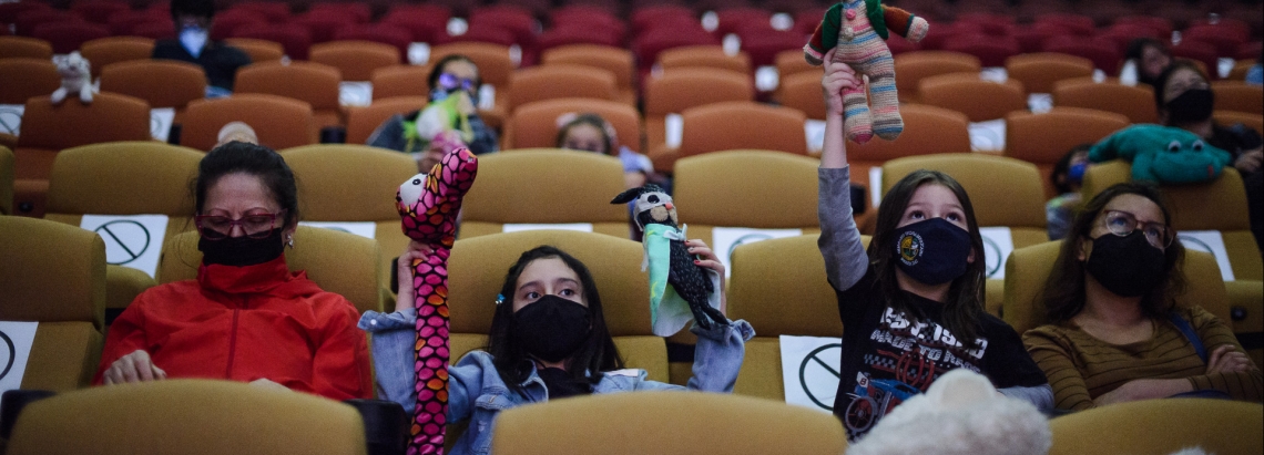 Niños y niñas sentados en la Cinemateca con títeres en las manos