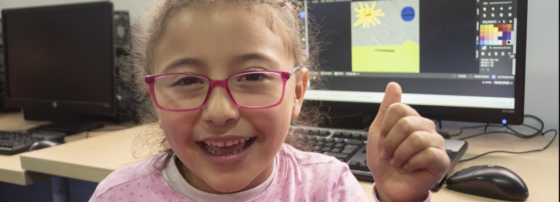 Una niña sonríe frente a un computador