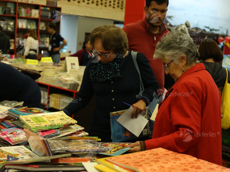 Mujeres viendo libros en estante Corferias - FILBo