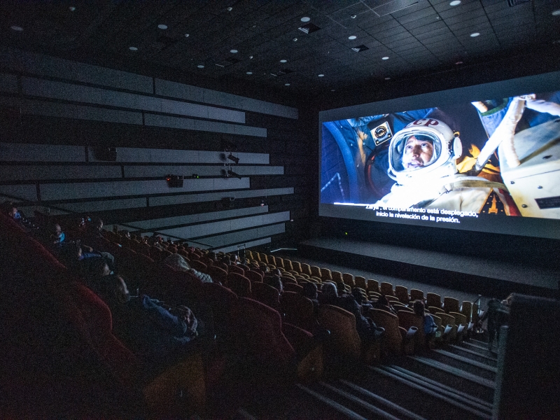 Sala oscura de Cinemateca con proyección de astronauta de fondo. 