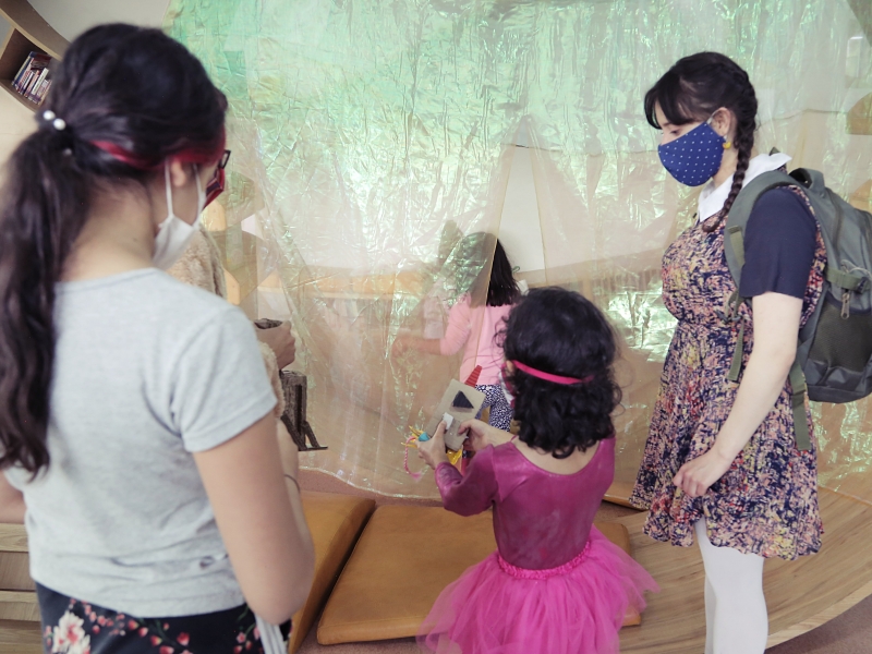 Artistas del Programa Nidos compartiendo con una niña en primera infancia durante experiencia artística.