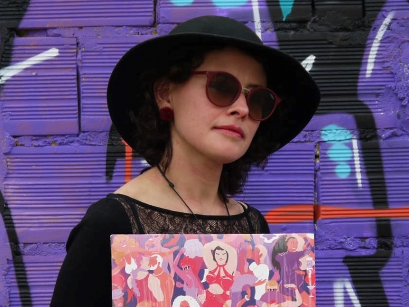 Mujer posando para la foto con disco en la mano, en fondo violeta