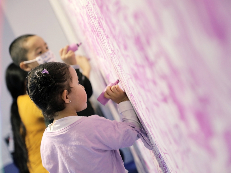 Niños escribiendo con crayola sobre una pared.