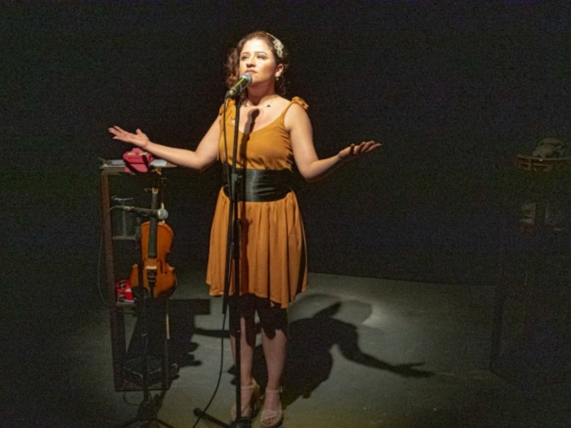 Fotografía de una mujer en escena cantando frente a un micrófono